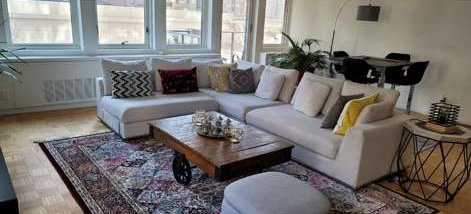 Living room with a corner sectional sofa, patterned rug and bay windows