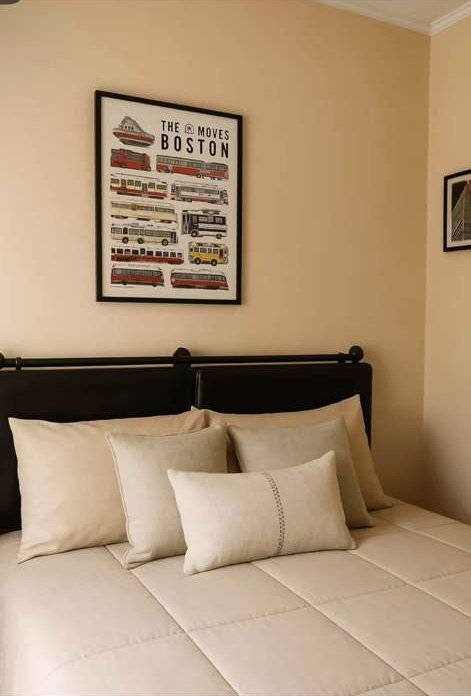 Bedroom with a framed print above the bed and layered cushions